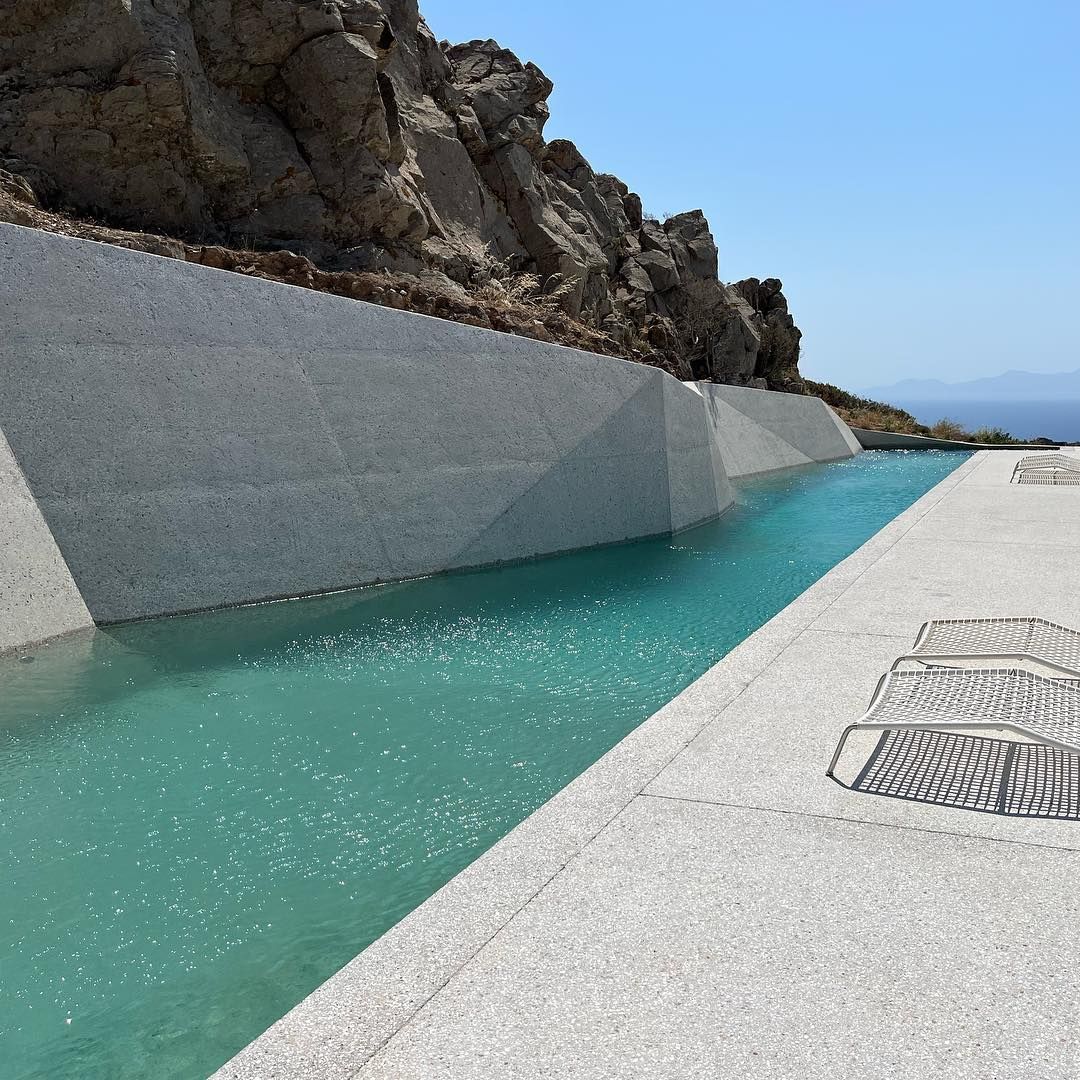 Piscina privada, estilo canal de natación, de diseño único y diferente junto a las rocas por Alpha Pools, en un espacio moderno y minimalista