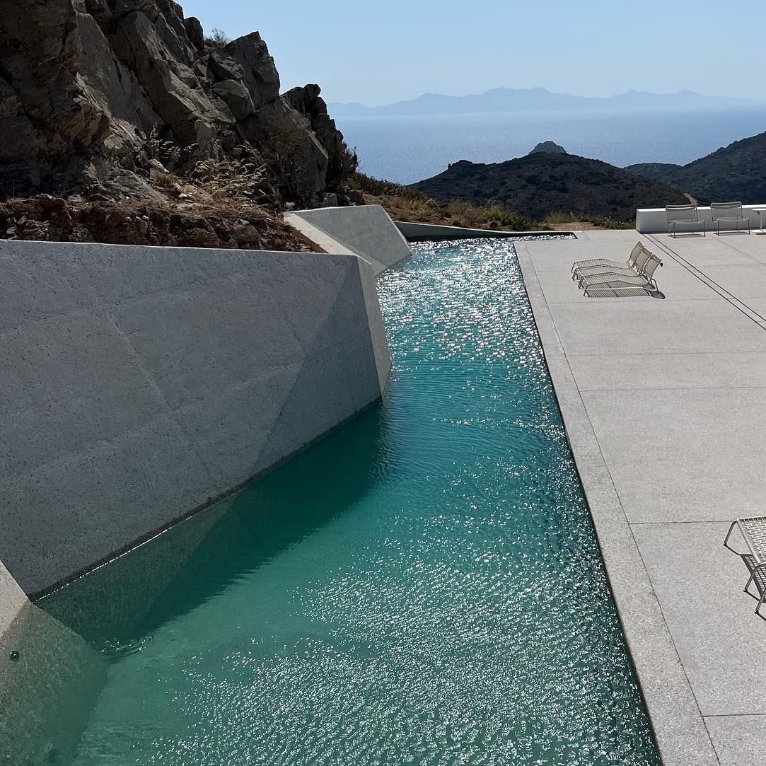 Piscina privada, estilo canal de natación, de diseño único y diferente junto a las rocas por Alpha Pools, en un espacio moderno y minimalista, con espectaculares vistas a la montaña