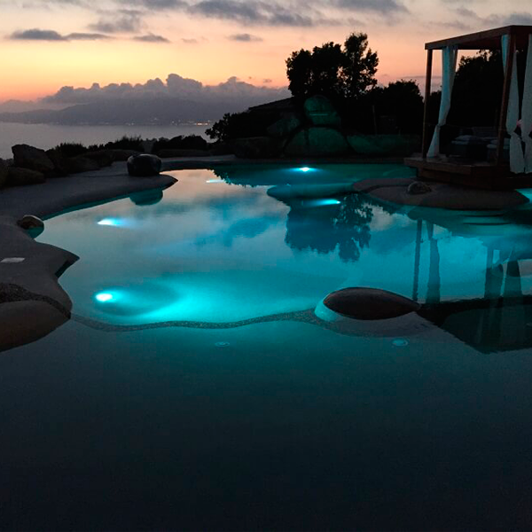 piscina tipo playa iluminada por la noche
