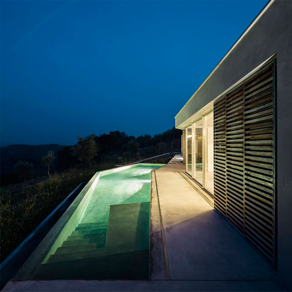 piscina infinity iluminada por la noche en una colina