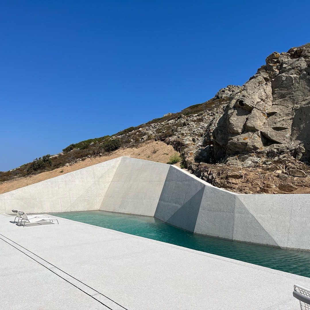 Piscina privada, estilo canal de natación, de diseño único y diferente junto a las rocas por Alpha Pools, en un entorno minimalista