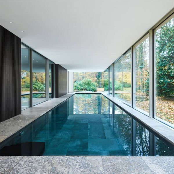 Piscina interior, de diseño minimalista e ideal para nadar, en un moderno proyecto de DDM Architectuur, con grandes ventanales
