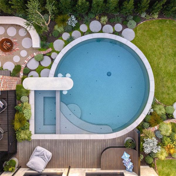 Vista dron de una piscina única, con spa integrado, de Exquisite Pools and Gardens, en un pequeño jardín en el que se combina el uso de círculos, líneas curvas y rectas
