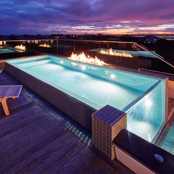 mini piscina desbordante con pared transparente, en la terraza de una casa moderna, por Kersting Architecture, iluminada por la noche