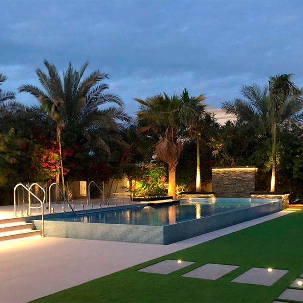 piscina infinity de diseño moderno y minimalista, por La Vita Landscaping and Pools, en un jardín de grandes dimensiones, iluminado por la noche