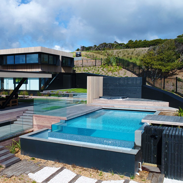 piscina infinity con pared transparente y entorno en tarima de madera