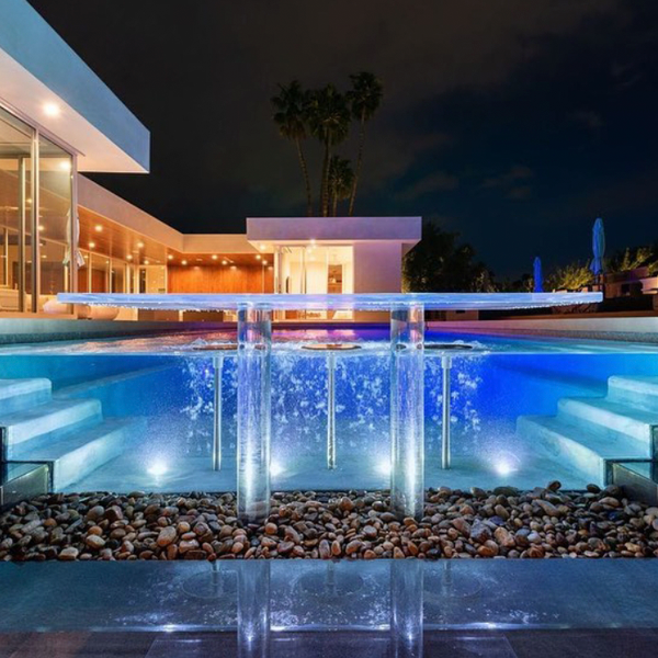 piscina desbordante con pared transparente por Melos Pools and Outdoors