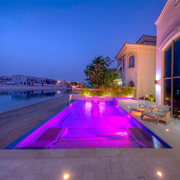 piscina desbordante a la playa con iluminación nocturna en tonos rosados