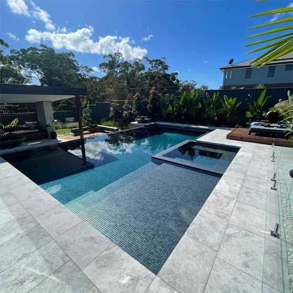 Elegante piscina infinity con spa integrado y revestimiento en tono grisáceo, por Splish Splash Pools, en un espacio de diseño moderno y minimalista