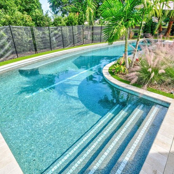 Piscina a medida con forma de L curvada y un enorme banco corrido a lo largo, con un revestimiento que le da al agua un precioso color turquesa, por Almar Jackson