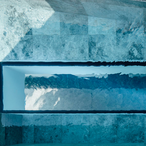 ventana en piscina a medida con revestimiento de mármol, por Aloha Pools