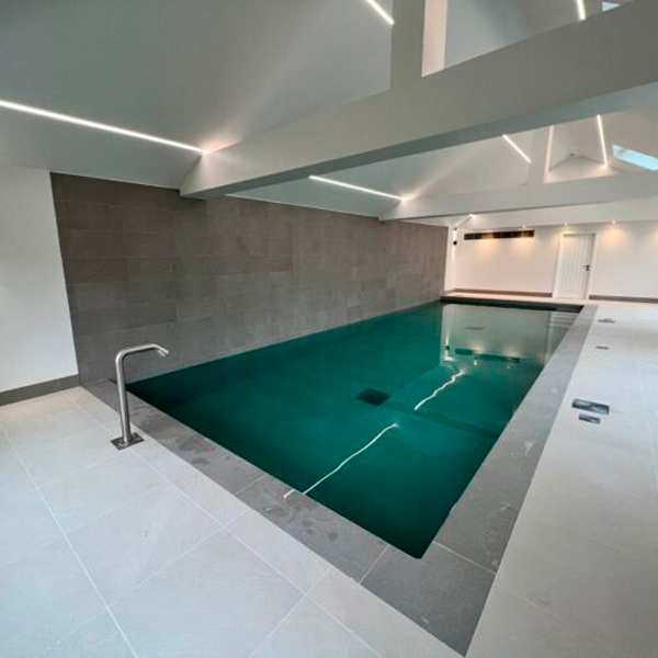piscina interior de diseño clásico rectangular, de Blue Cube Pools, con un cañón de agua, equipo de natación contracorriente y color contraste al espacio del sótano
