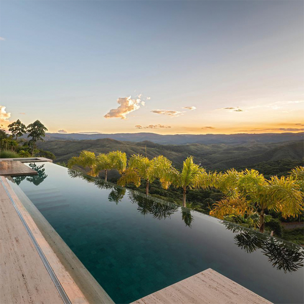 Moderna piscina infinita de diseño minimalista, estilo canal de natación, en un proyecto de Boechat Casas, con espectaculares vistas al atardecer