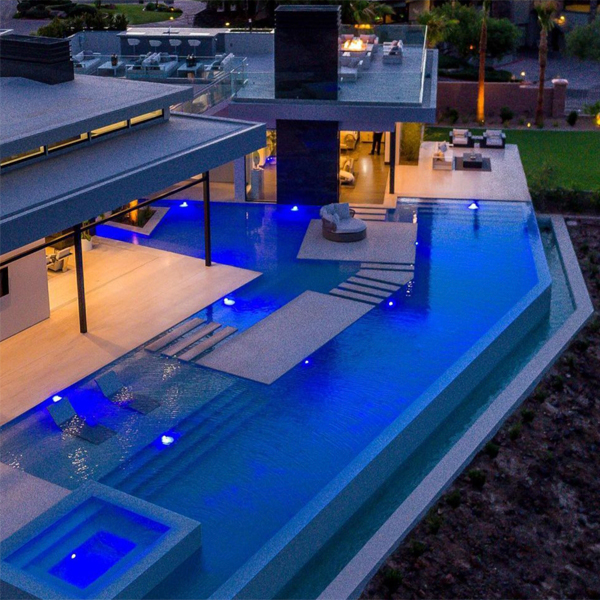 piscina infinity de lujo con spa integrado iluminada por la noche, de California Pools