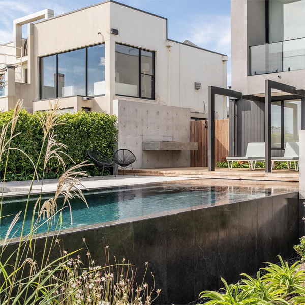 piscina infinity con spa incorporado con revestimiento en tonos oscuros, por Coastal Pools and Spas