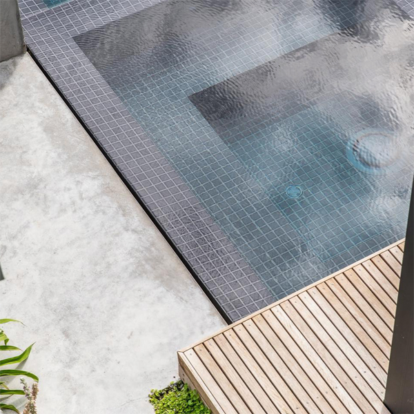 combinación de gresite, piedra natural y tarima de madera en piscina infinity con spa, de Coastal Pools and Spas