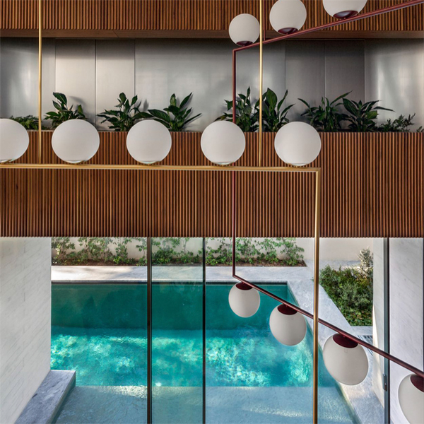 vista de una piscina moderna y minimalista desde el interior del salón de la casa, en un proyecto de Divercity Architects