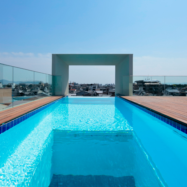 Piscina infinita con ventanas en el fondo, y un arco exterior, que hace las veces de marco de un cuadro, ubicada en la terraza de un moderno proyecto de vivienda, de estilo minimalista, por Eastern Design Office