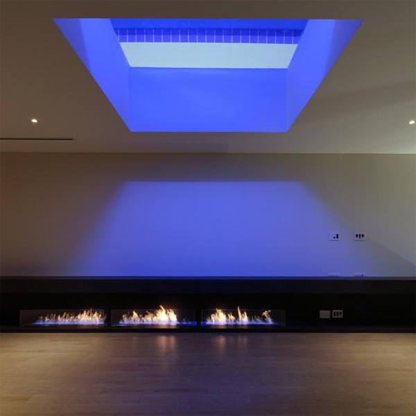 Vista del salón de una casa de diseño moderno con pequeñas hogueras, de Eastern Design Office, con una ventana en el techo, a través de la cual se puede ver la piscina iluminada