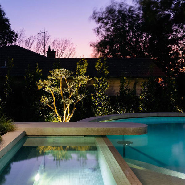 elegante piscina de Exquisite Pools and Gardens, iluminada por la noche en un moderno jardín