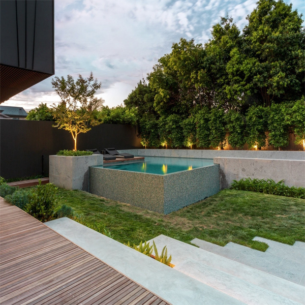 mini piscina infinita de diseño, de Feature Pools, en un moderno jardín con una genial combinación de materiales, al atardecer
