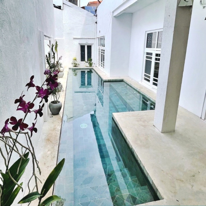 Piscina desbordante, con revestimiento en piedra bali, construida en un espacio muy reducido por Foster and Reed