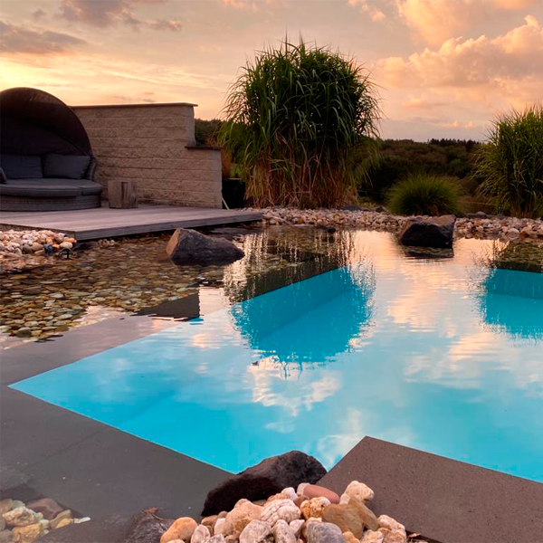 piscina con desbordamiento rodeada de piedras sumergidas, en el listado de las mejores piscinas del verano 2022, por Gartengestaltung Porten