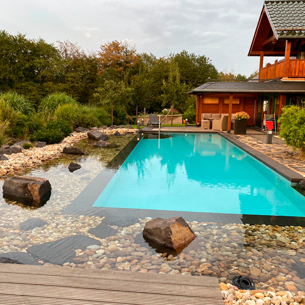 piscina con desbordamiento rodeada de piedras sumergidas por Gartengestaltung Porten