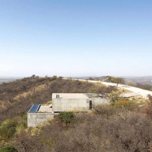 Vista dron de vivienda moderna y minimalista con piscina infinity, por Gastón Sironi Arquitectos, situada en una colina
