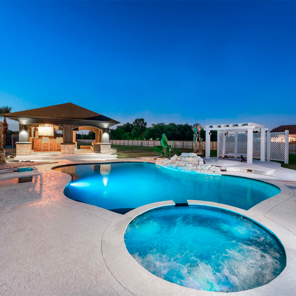 piscina negra con spa, iluminada por la noche, de J´s Pools and Spas