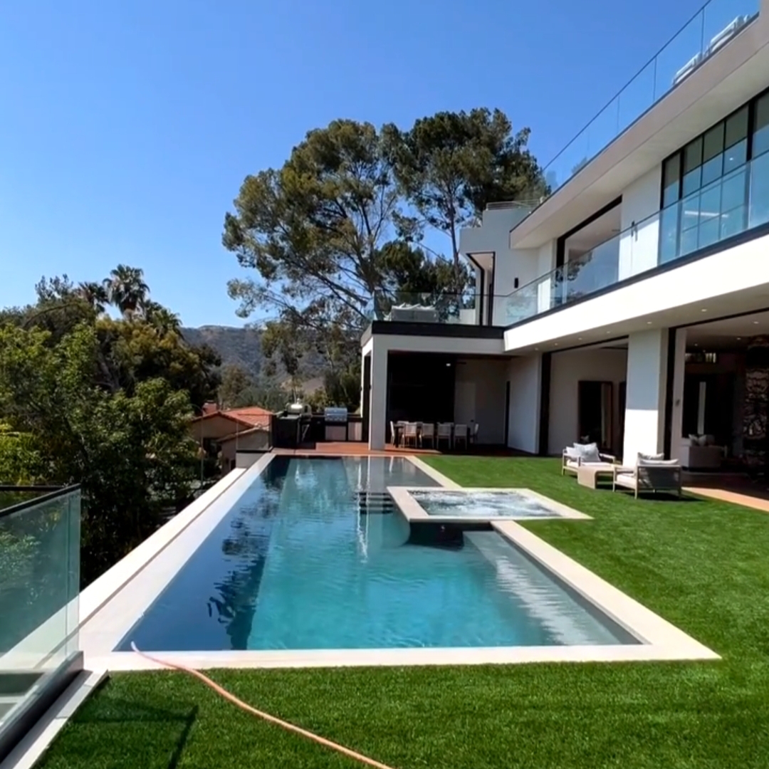 Piscina infinita, estilo canal de natación, con spa incorporado, por Jabs Pools, en el jardín de una casa moderna en una colina