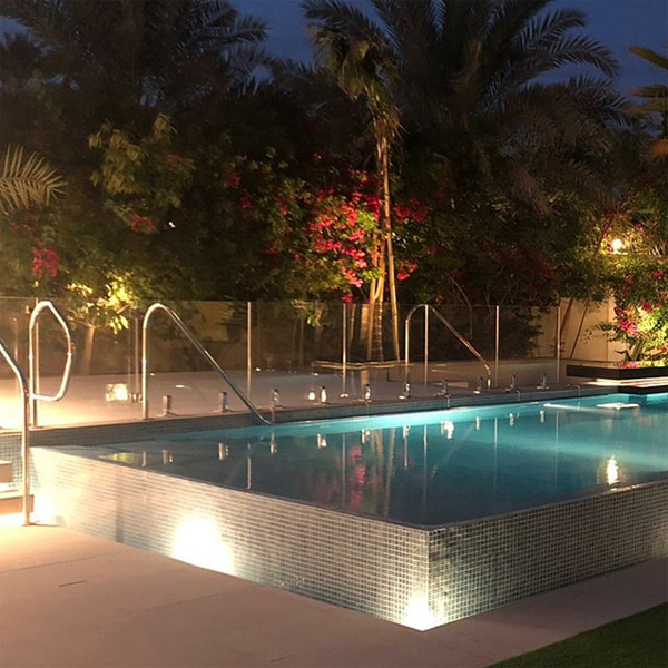 piscina infinity de diseño moderno y minimalista, por La Vita Landscaping and Pools, iluminada por la noche, en un jardín de grandes dimensiones
