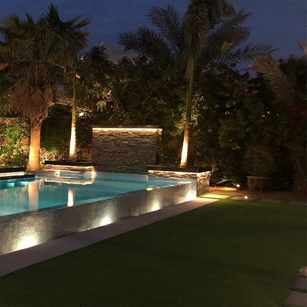 piscina infinity de diseño moderno y minimalista, por La Vita Landscaping and Pools, en un jardín de grandes dimensiones, iluminado por la noche
