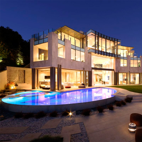 piscina infinity a medida iluminada por la noche, con spa incorporado, en un proyecto de Landry Design Group