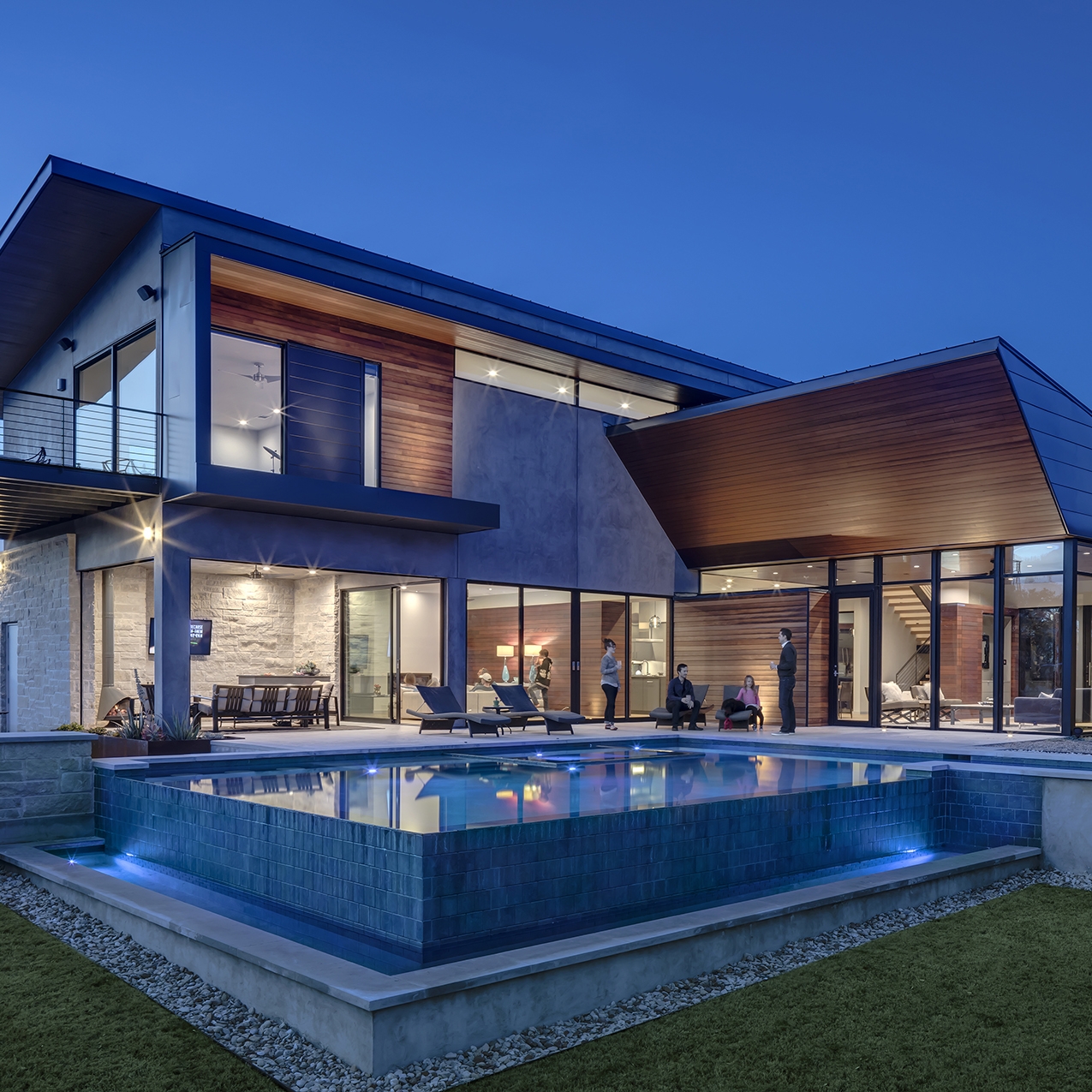 Piscina infinta iluminada por la noche, en una casa moderna, diseñada a dos alturas, por MF Architecture