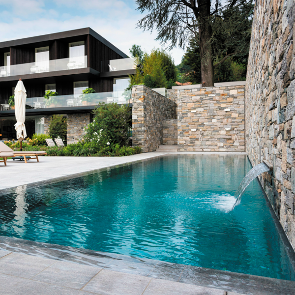 piscina desbordante con cascada en muro de piedra