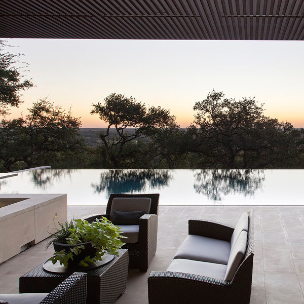Vista de una piscina espejo al atardecer, desde el salón exterior de un proyecto de Murray Legge Architecture