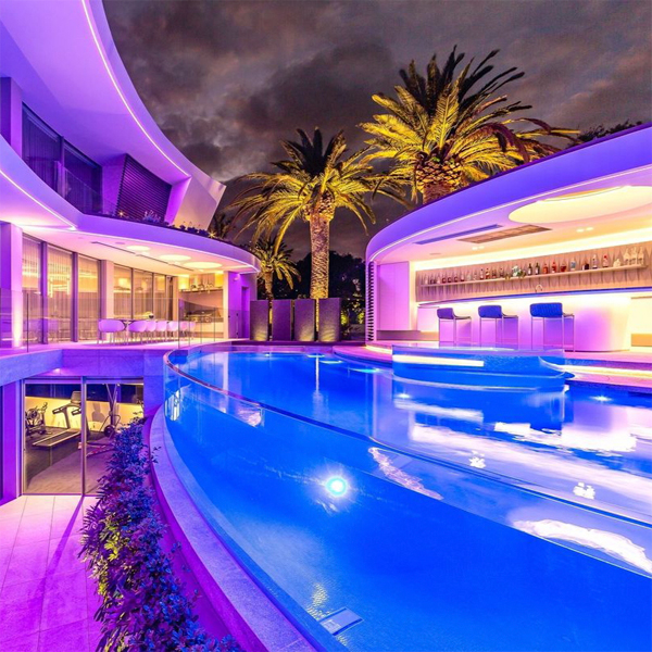 Una piscina transparente única, iluminada por la noche, con spa incorporado, por Personal Pools