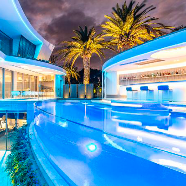 Una piscina transparente única, iluminada por la noche, con spa incorporado, por Personal Pools