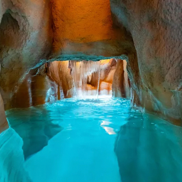 piscina interior imitando una cueva, con diferentes juegos de agua y cascadas, dentro de un complejo hotelero, por Piscines Ondine