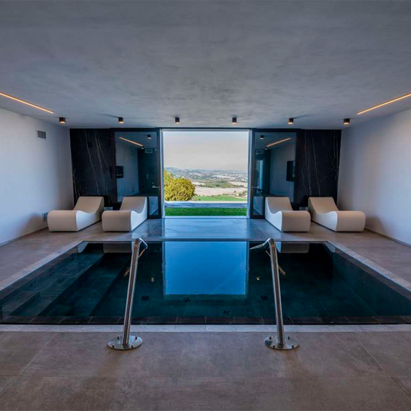 mini piscina desbordante en el interior de una vivienda con cañones de agua y spa interior, por Professione Piscina