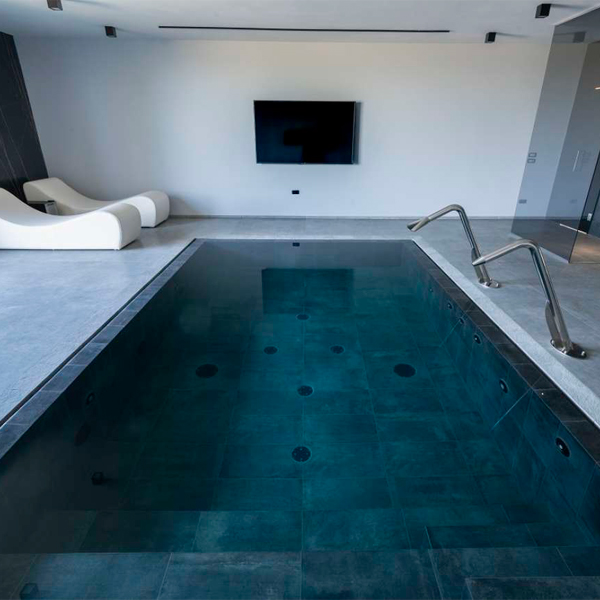 mini piscina desbordante en el interior de una vivienda con cañones de agua y spa interior, por Professione Piscina