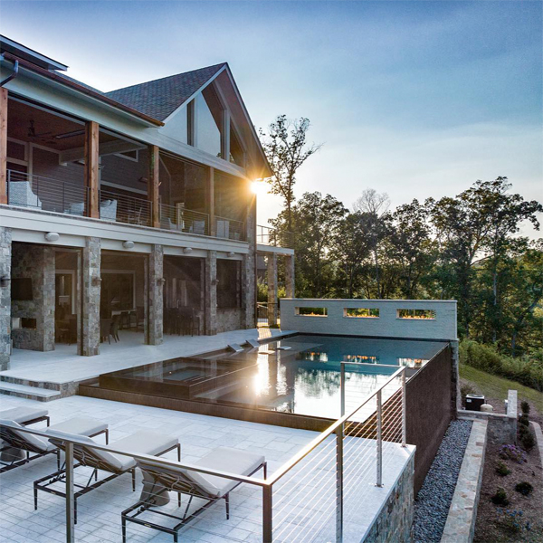 piscina infinita de revestimiento oscuro, con spa integrado, por Signature Luxury Pools, ubicada en una moderna terraza de diseño minimalista, al atardecer