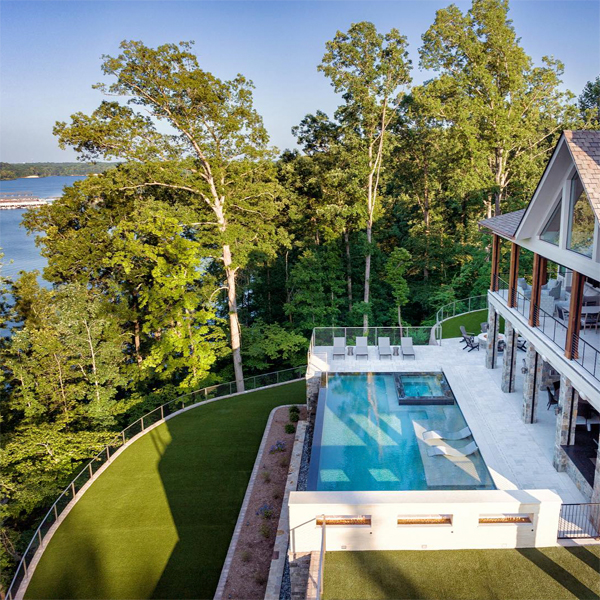 vista dron de espectacular piscina infinity de Signature Luxury Pools, en una moderna casa con mucha vegetación y unas estupendas vistas al lago