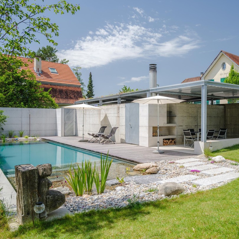 Bio piscina, de diseño tradicional rectangular, en un jardín de diseño moderno y depurado, por la empresa suiza Stieger