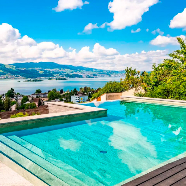 Piscina infinita de lujo a medida, con cascada de acero inoxidable y espectaculares vistas sobre el lago, por Vita Bad