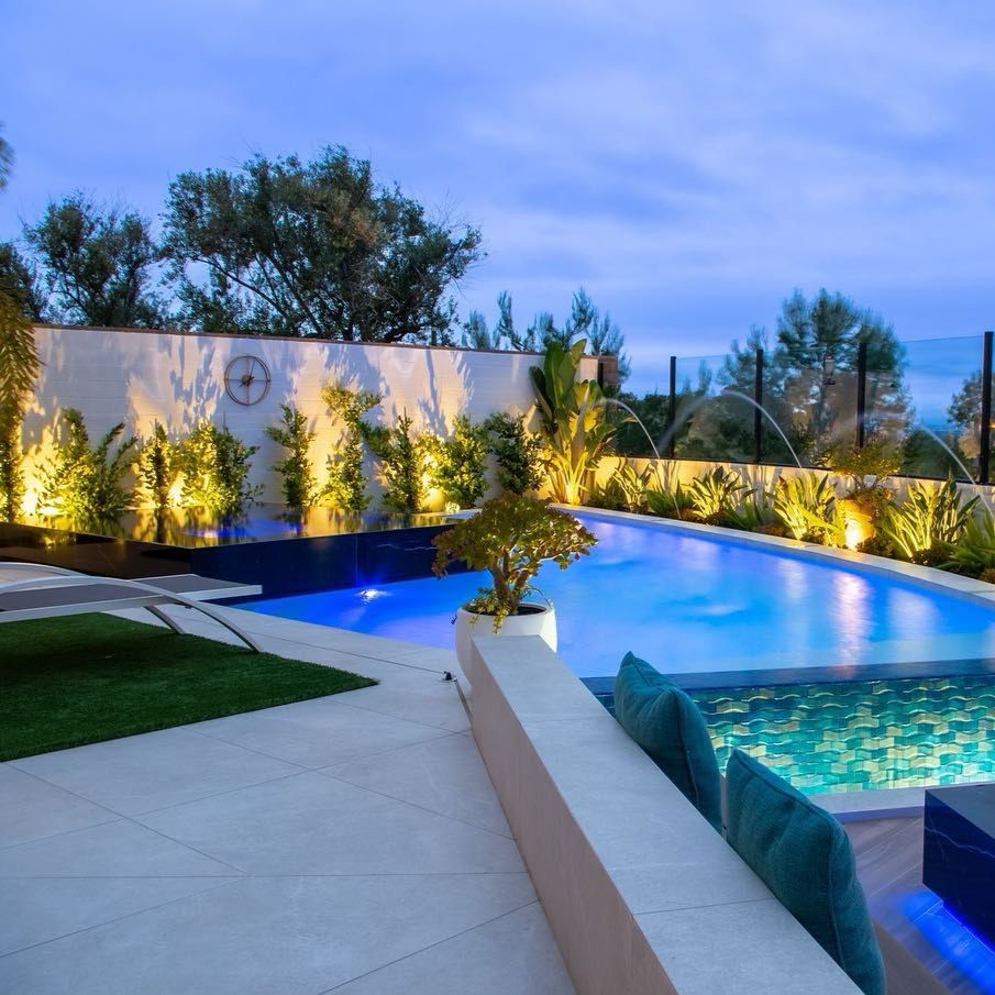 Impressionnant projet de piscine à débordement avec spa surélevé contrasté, par Coastline Pools, éclairée la nuit, dans un jardin à la décoration minimaliste