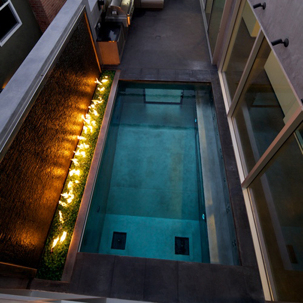 Mini piscine inox avec parois vitrées, à côté d'un espace avec feu, dans un projet d´une maison moderne par David Hertz Architects FAIA