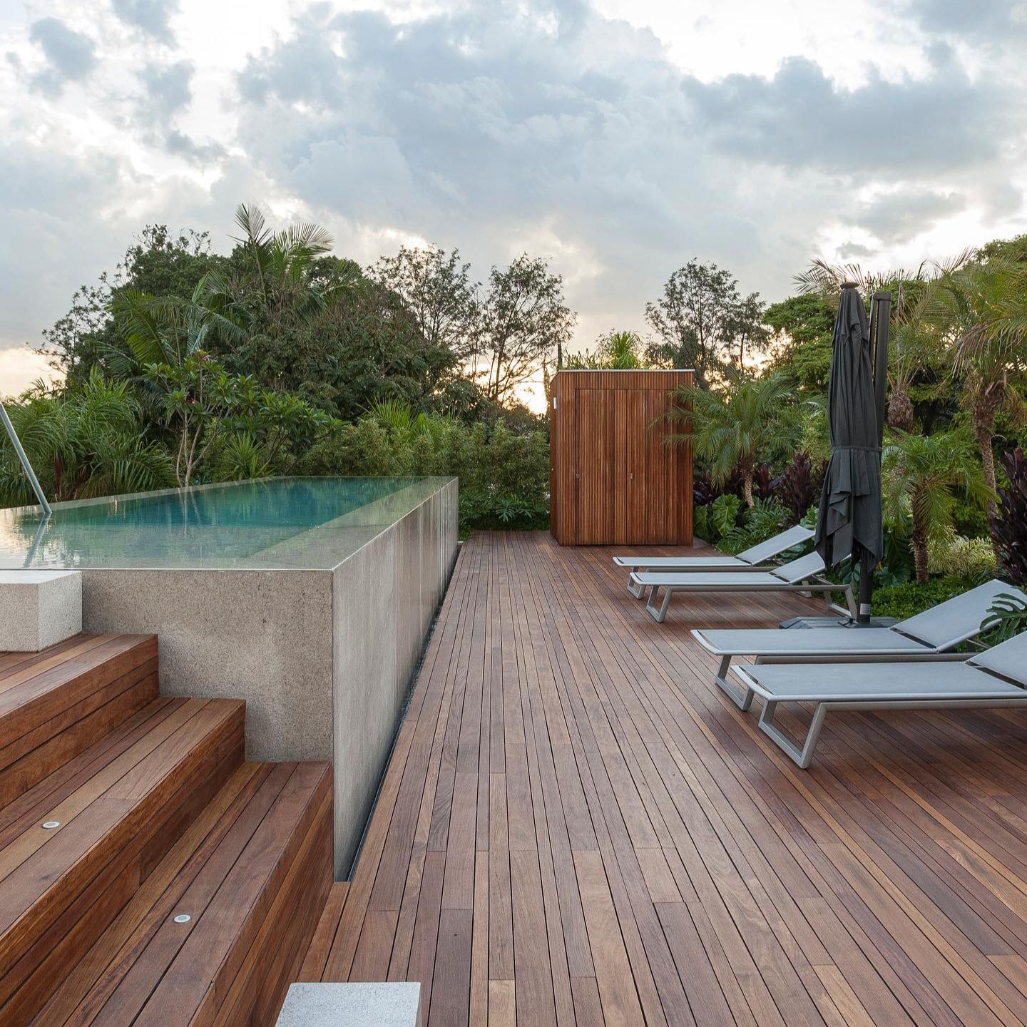 Piscine à débordement hors sol dans une terrasse en bois, dans un projet par DB Arquitetos