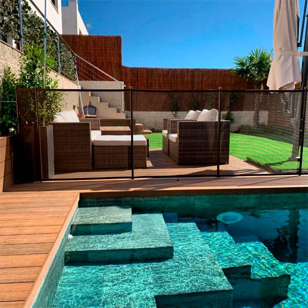 Piscine privée au design classique et revêtement en grès cérame, entourée d'une terrasse en bois synthétique, dans un projet Piscinas Los Hermanos, dans un petit jardin avec gazon artificiel